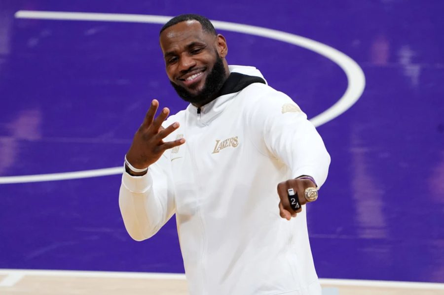 LeBron James smiling courtside in a Los Angeles Lakers hoodie